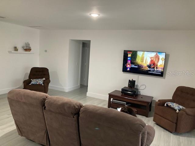 A living room features a brown sofa, two recliners, and a wall-mounted television — 18312 DRIGGERS AVENUE, PORT CHARLOTTE, FL