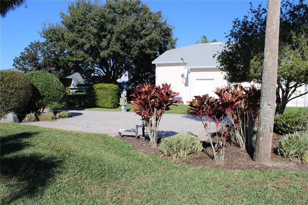 A paved driveway leads to a light-colored house with landscaping and mature trees — 352 TRAVELERS DRIVE, POLK CITY, FL