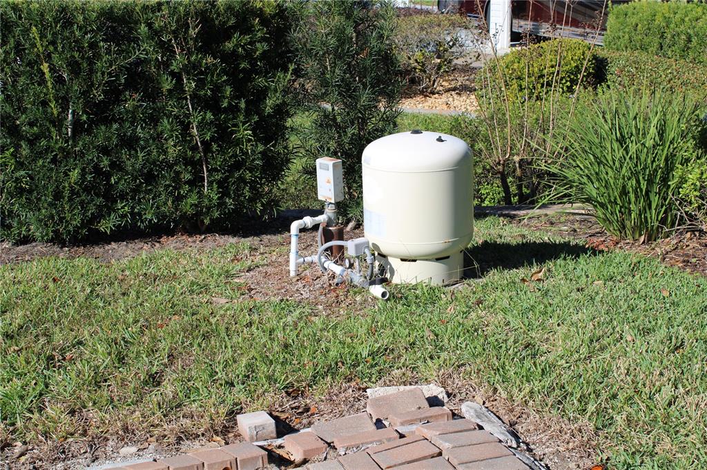 A residential water well pressure tank and pump system sit in a landscaped yard — 352 TRAVELERS DRIVE, POLK CITY, FL