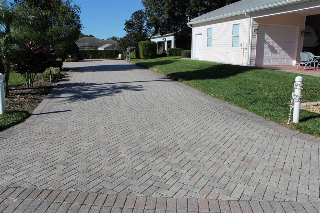 A paved herringbone driveway leads toward a light-colored house with a garage — 352 TRAVELERS DRIVE, POLK CITY, FL