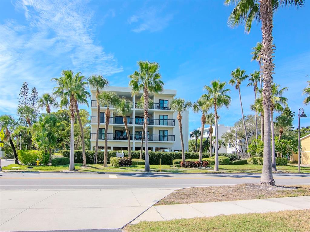 A multi-story apartment building stands behind a row of palm trees along a street — 3200 GULF BOULEVARD UNIT 103, ST PETE BEACH, FL