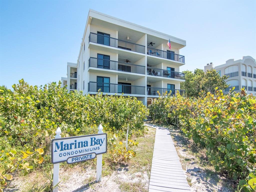 A multi-story condominium building stands behind a wooden walkway and a private property sign — 3200 GULF BOULEVARD UNIT 103, ST PETE BEACH, FL