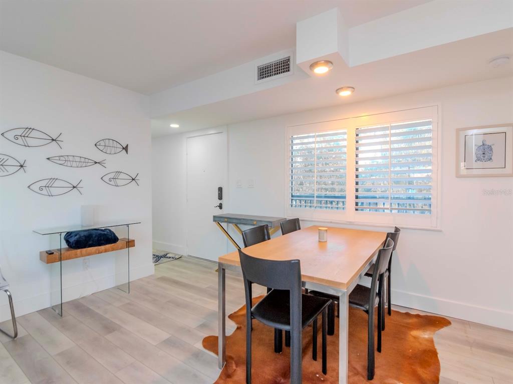 A dining area features a wooden table, black chairs, a cowhide rug, and wall art — 3200 GULF BOULEVARD UNIT 103, ST PETE BEACH, FL