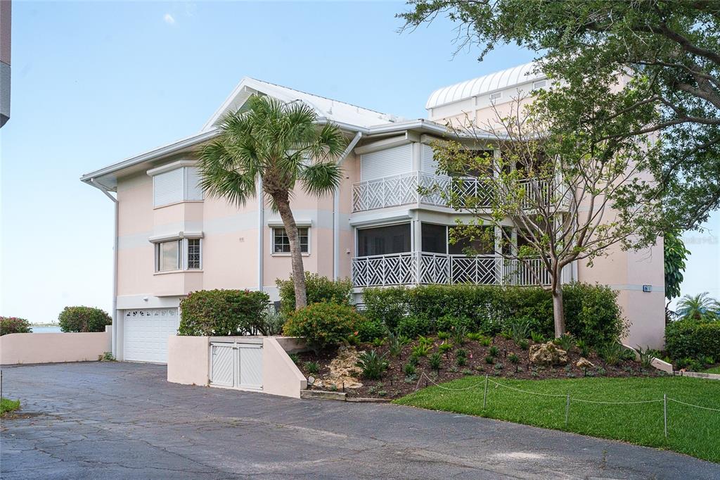 A multi-story pink residential building with a driveway, palm tree, and screened balconies — 11000 PLACIDA ROAD UNIT 101, PLACIDA, FL