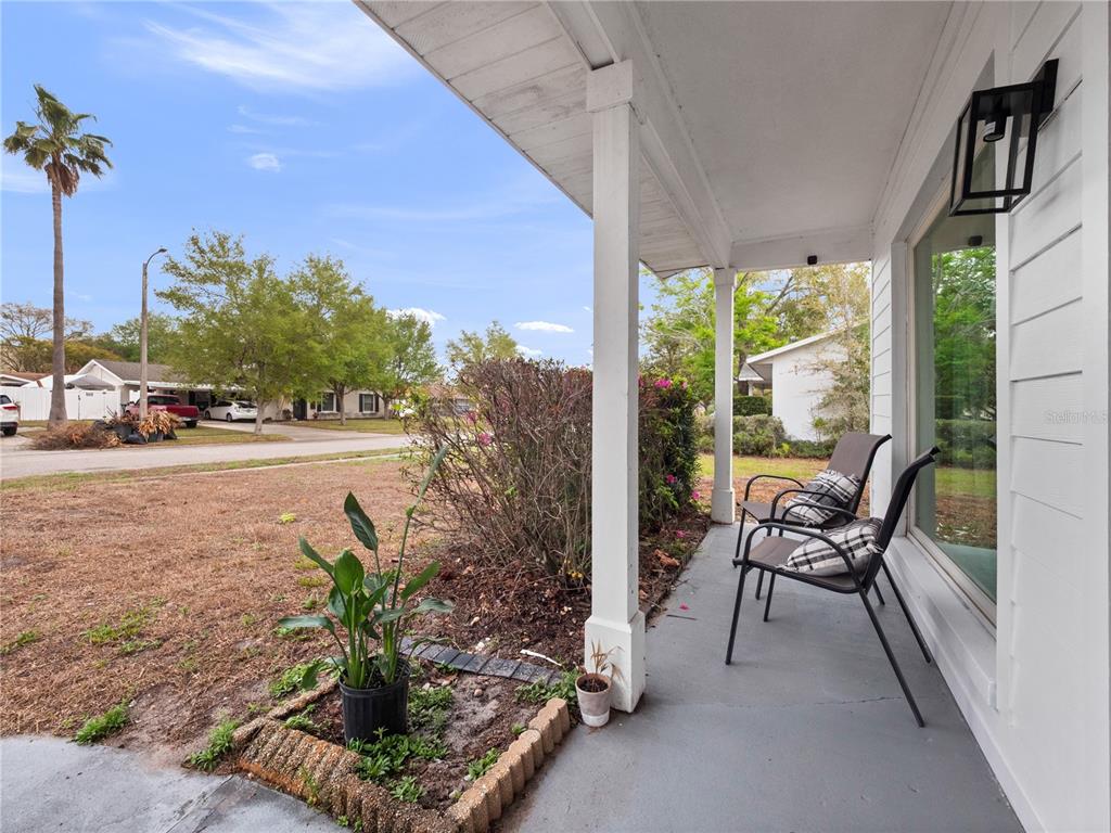 A covered front porch features two chairs, a small garden bed, and a white pillar — 2733 MIDDLE STREET, ORLANDO, FL