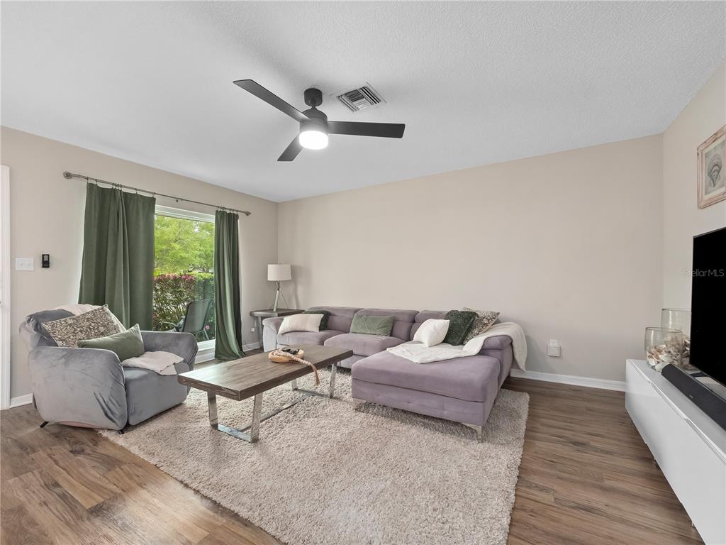 A living room features a gray sectional sofa, an armchair, a coffee table, and wood flooring — 2733 MIDDLE STREET, ORLANDO, FL