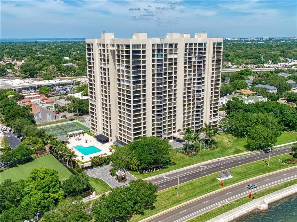An aerial view shows a tall residential high-rise building with a pool and tennis courts — 3301 BAYSHORE BOULEVARD UNIT 1904D, TAMPA, FL