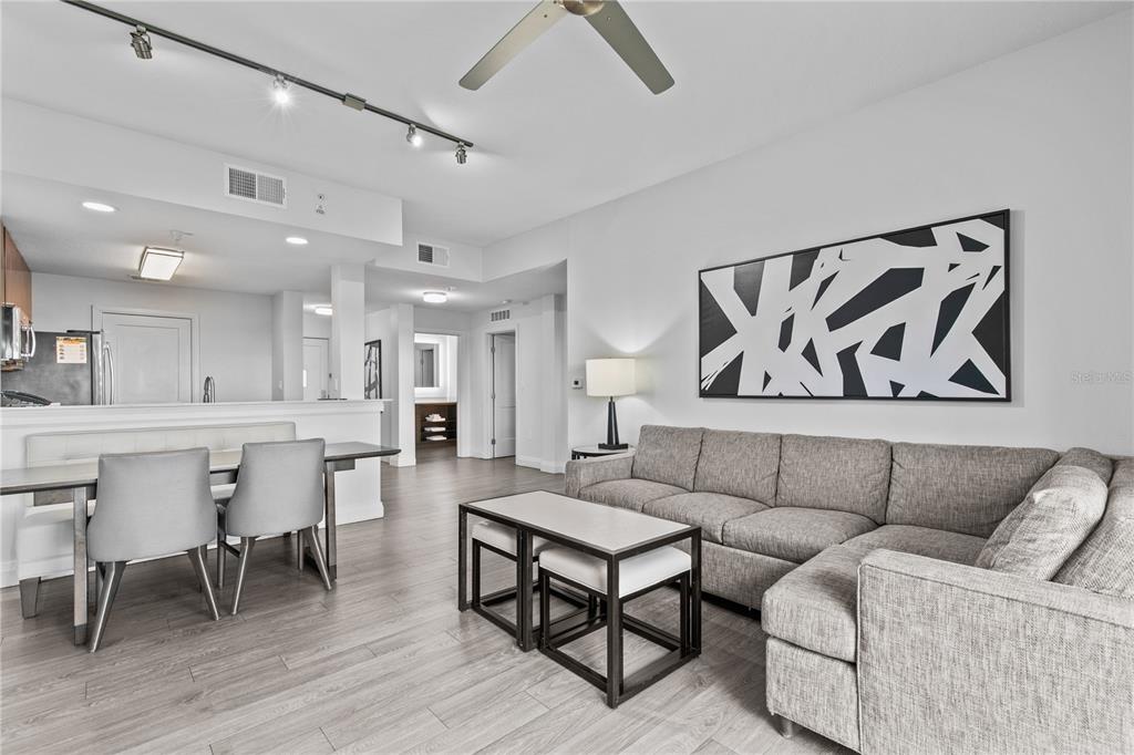 A living room and dining area with gray wood floors, a sectional sofa, and track lighting — 14501 GROVE RESORT AVENUE UNIT 3619, WINTER GARDEN, FL