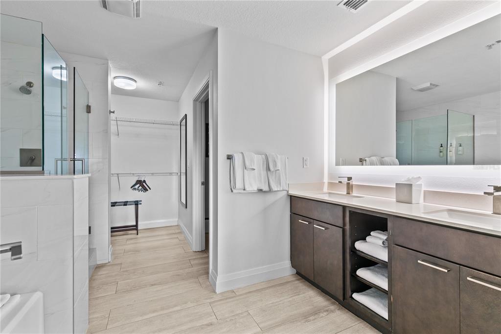 A modern bathroom features a double vanity, a walk-in closet, and a glass-enclosed shower — 14501 GROVE RESORT AVENUE UNIT 3619, WINTER GARDEN, FL