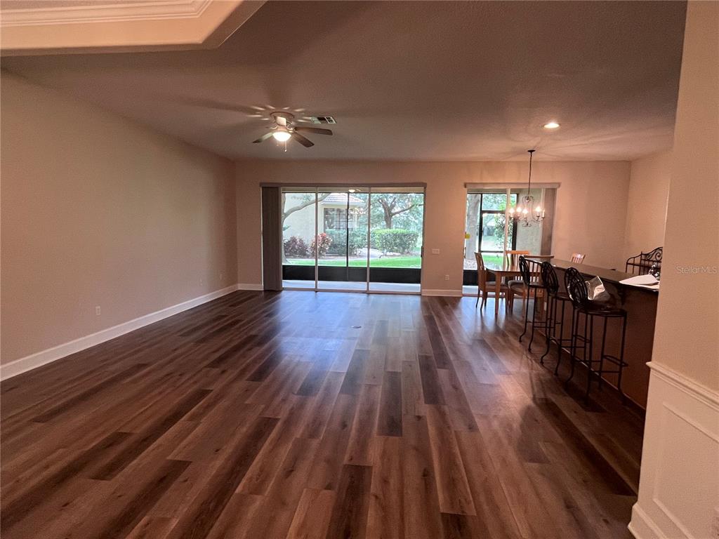 An open-concept living area features wood-look flooring, a ceiling fan, and sliding glass patio doors — 8280 VIA VIVALDI, ORLANDO, FL
