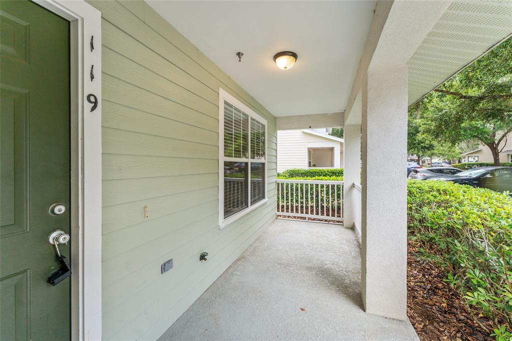 A covered concrete porch features light green siding, a green front door, and white railings — 4680 SW 48TH WAY UNIT 119, GAINESVILLE, FL