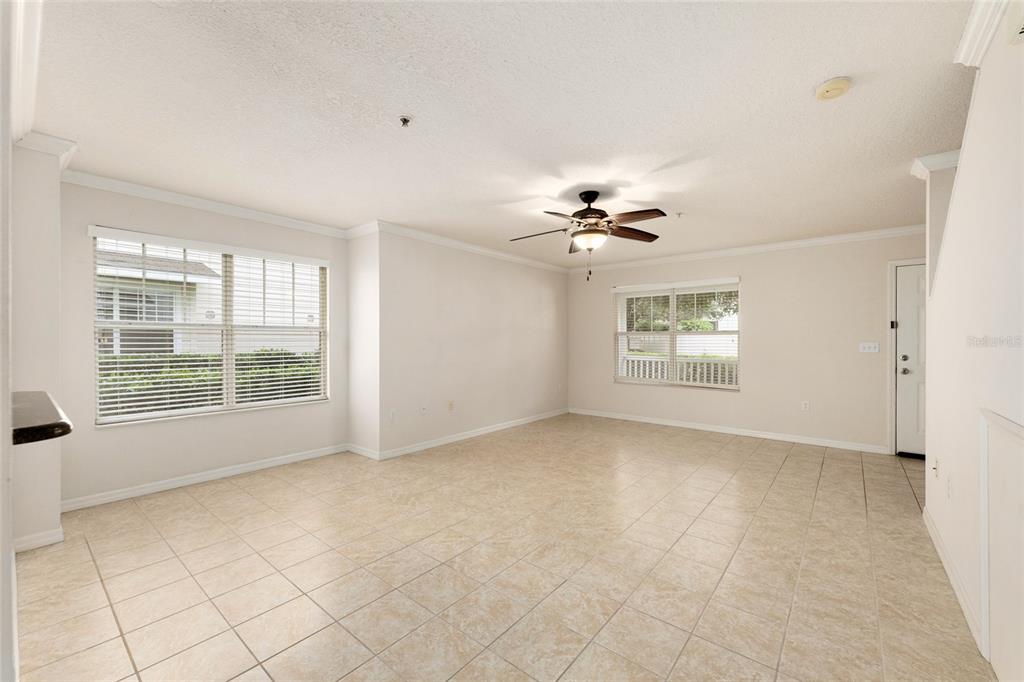 A bright, empty living room features beige tile flooring, white walls, and a ceiling fan — 4680 SW 48TH WAY UNIT 119, GAINESVILLE, FL
