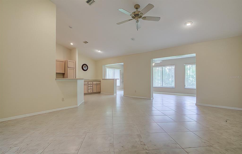 An open-concept living area features light-colored tile flooring, beige walls, and a ceiling fan — 12 ANTON COURT, HOMOSASSA, FL