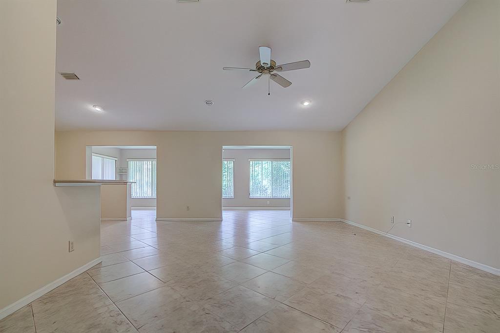 A spacious, empty room with beige walls, tile flooring, and a ceiling fan — 12 ANTON COURT, HOMOSASSA, FL