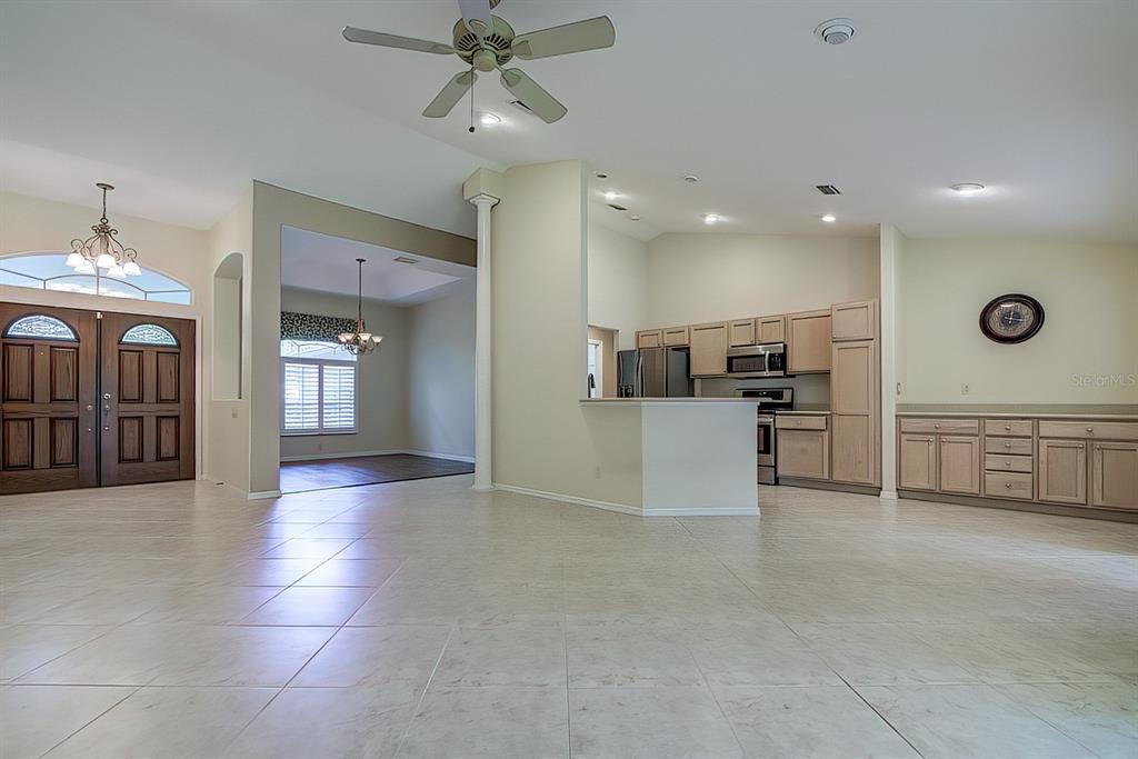An open-concept living area features light tile flooring, a kitchen with wood cabinets, and an entryway — 12 ANTON COURT, HOMOSASSA, FL