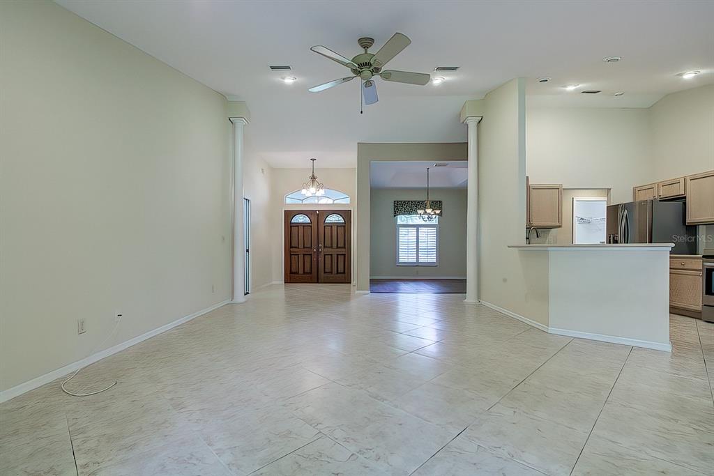 A spacious living area with tile flooring, white walls, two columns, and an open kitchen — 12 ANTON COURT, HOMOSASSA, FL
