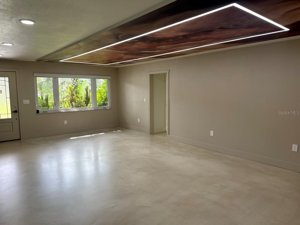 A room with a polished concrete floor, beige walls, and a recessed wood-paneled ceiling feature — 3197 WALNUT STREET NE, ST PETERSBURG, FL