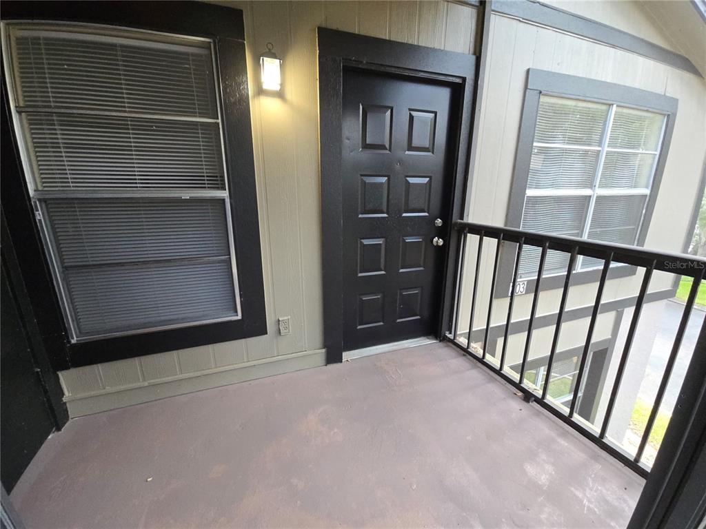 An exterior view of an apartment balcony with a black door and window trim — 4031 TUMBLE WOOD TRAIL UNIT 203, TAMPA, FL