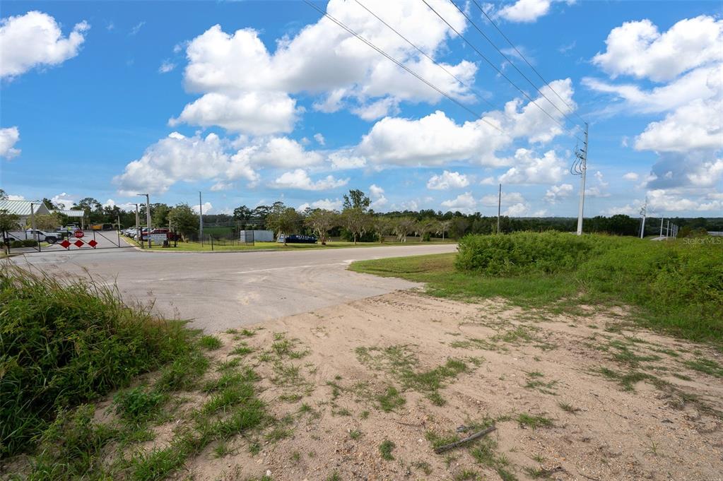 A paved road intersection meets a sandy, unpaved area under a bright, cloudy sky — 13157 NW 104TH TERRACE, ALACHUA, FL