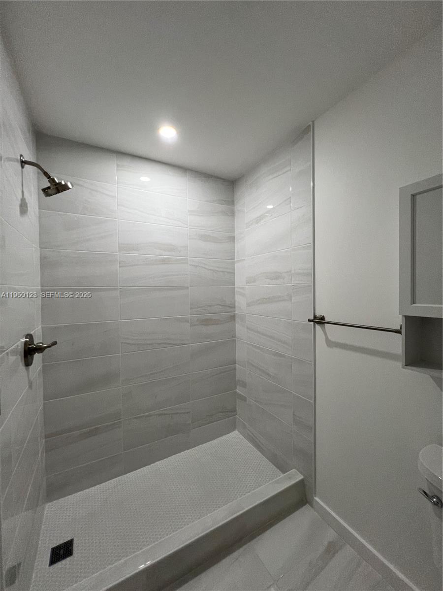 A walk-in shower features light-colored horizontal wall tiles, a mosaic floor, and brushed nickel fixtures — 8111 SW 81st Pl, Miami FL 33143, MIAMI, FL