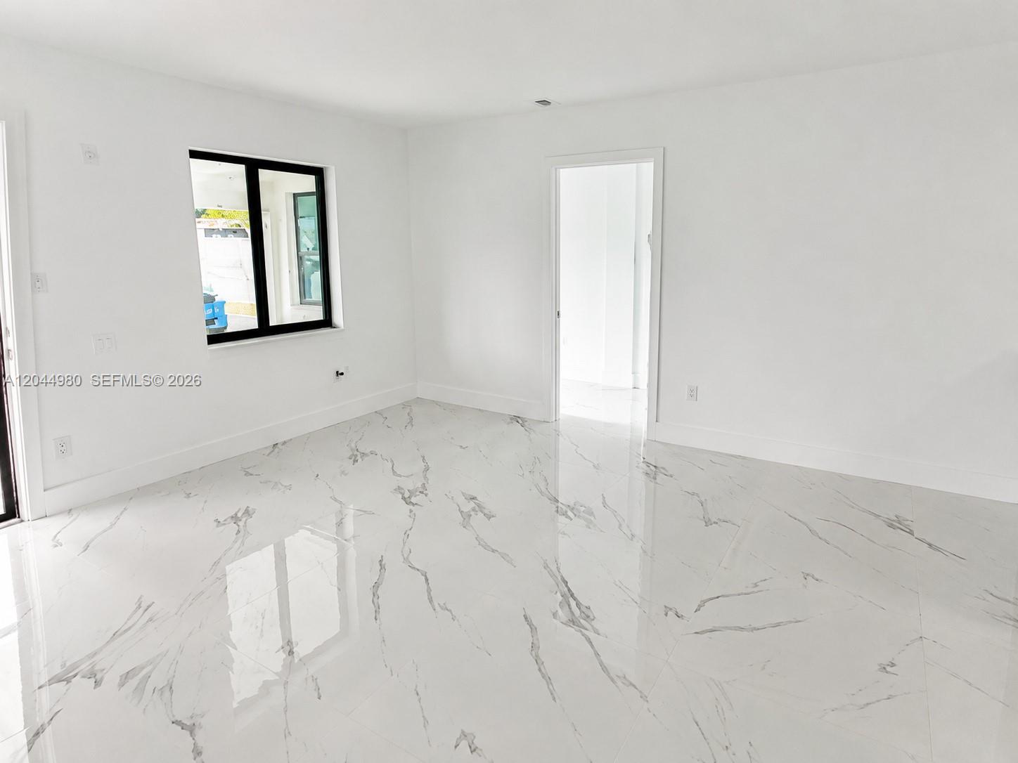 A bright, empty room features white walls, a window, a doorway, and marble-patterned tile flooring — 3435 SW 91st Ave # 0, Miami FL 33165, MIAMI, FL