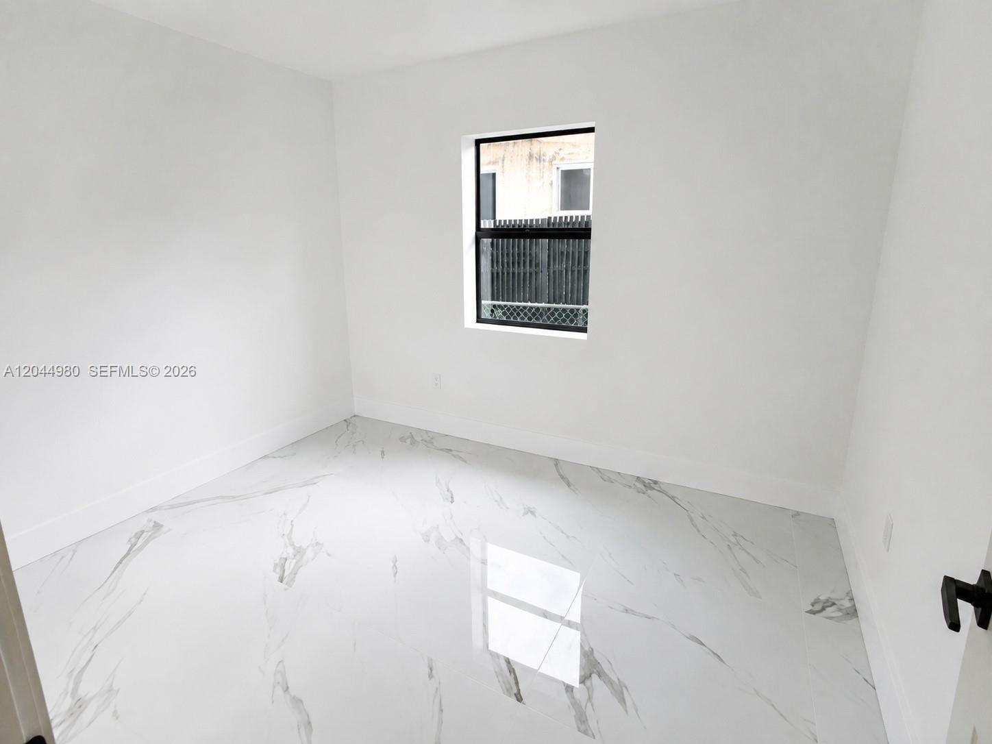 A small, empty room features white walls, white marble-look tile flooring, and a single window — 3435 SW 91st Ave # 0, Miami FL 33165, MIAMI, FL