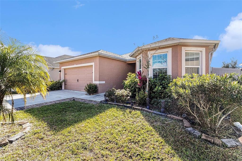 A single-story house with a tan stucco exterior, a garage, and a landscaped front yard — 769 FOREST TRACE CIRCLE, TITUSVILLE, FL