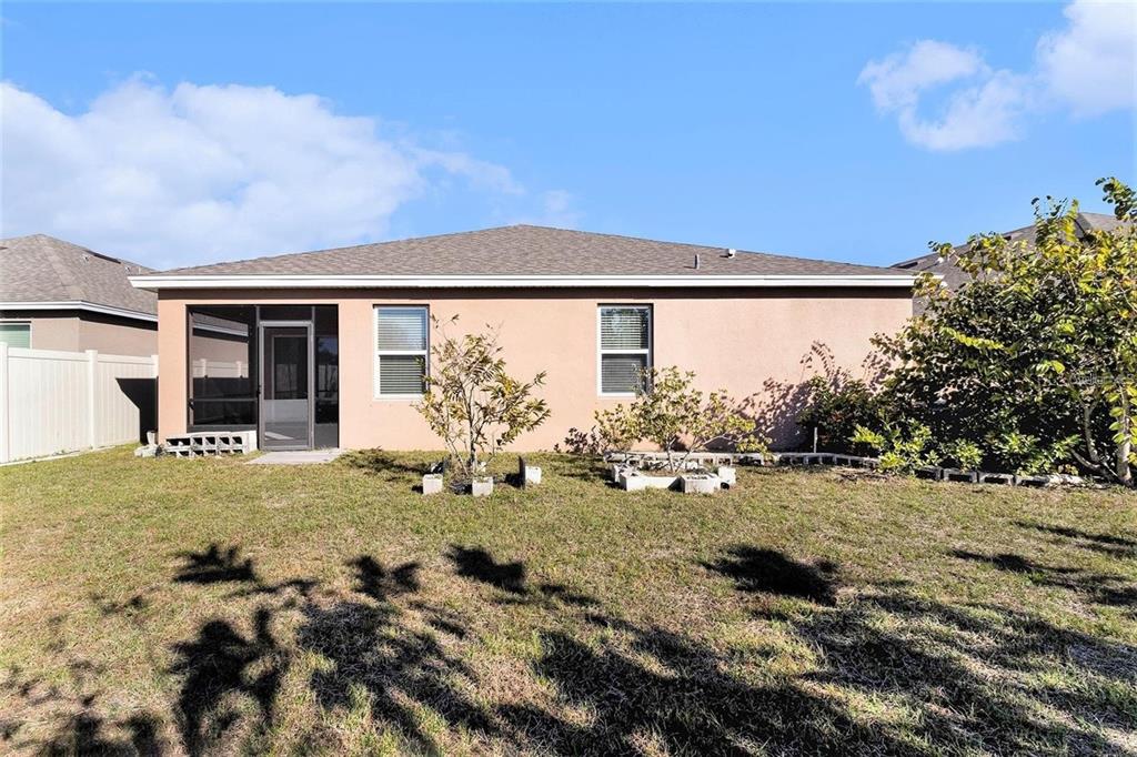 The rear exterior of a single-story house features a screened-in patio and a grassy yard — 769 FOREST TRACE CIRCLE, TITUSVILLE, FL