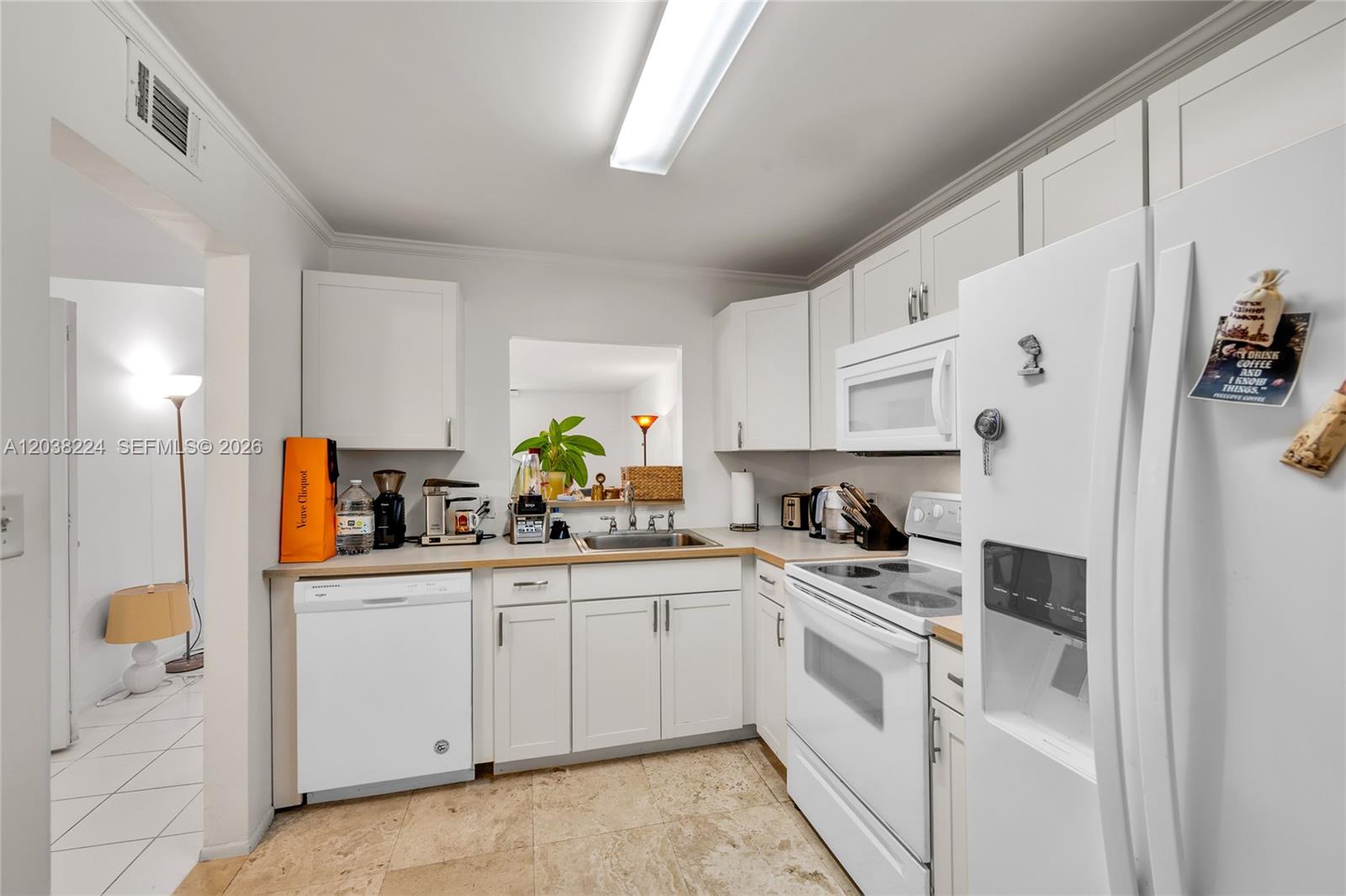 A kitchen features white cabinets, white appliances, and light-colored tile flooring — 1020 Meridian Ave # 715, Miami Beach FL 33139, MIAMI BEACH, FL