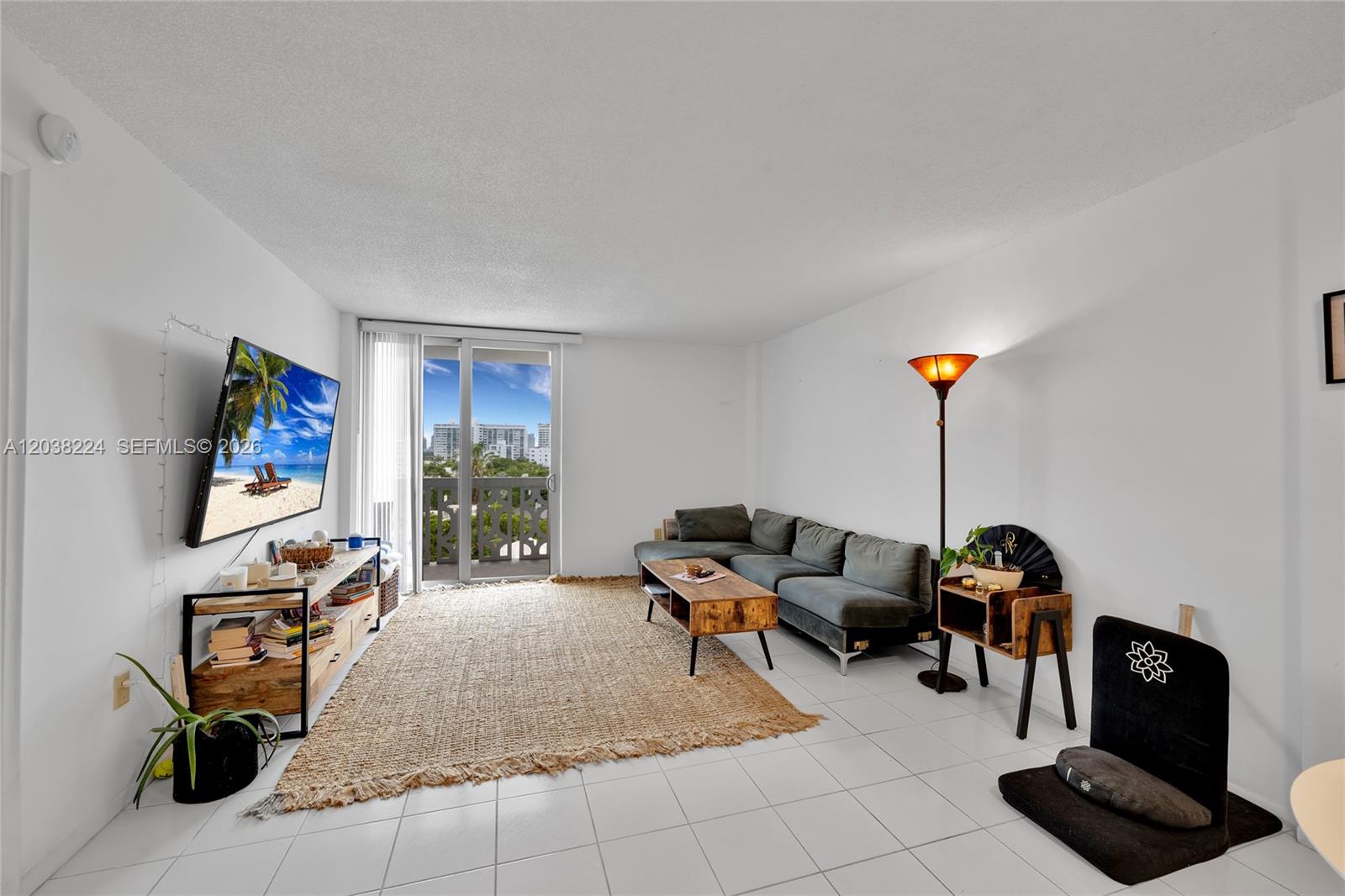 A living room features a grey sectional sofa, a jute rug, and a balcony view — 1020 Meridian Ave # 715, Miami Beach FL 33139, MIAMI BEACH, FL