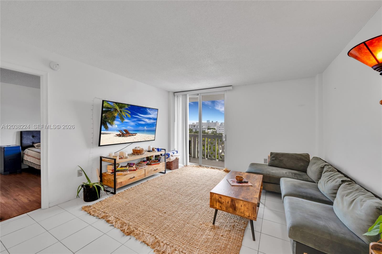 A living room features white tile floors, a jute rug, a sectional sofa, and a balcony — 1020 Meridian Ave # 715, Miami Beach FL 33139, MIAMI BEACH, FL