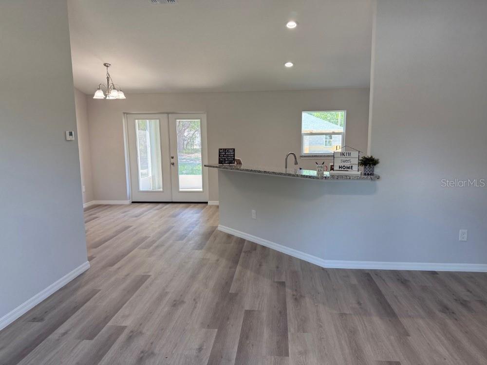 A kitchen with a granite breakfast bar overlooks a dining area with wood-look flooring — 13330 SW 111 LANE, DUNNELLON, FL