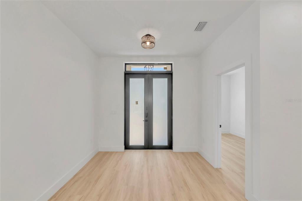 An entryway with light wood flooring, white walls, and a modern double front door — 1274 RONALD STREET, NORTH PORT, FL