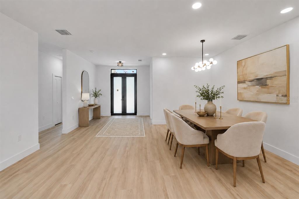 A dining area with a wooden table and chairs sits adjacent to a bright entryway — 1274 RONALD STREET, NORTH PORT, FL
