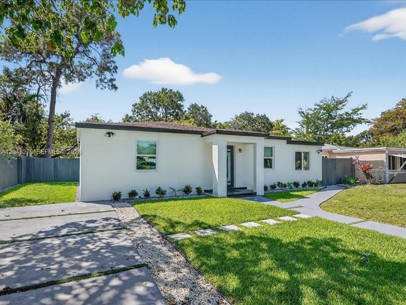 A single-story white house features a flat roof, a concrete driveway, and a grassy lawn — 1010 NE 138th St, North Miami FL 33161, NORTH MIAMI, FL