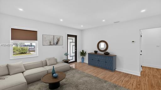A living room with a beige sectional, blue cabinet, and wood-look flooring — 1010 NE 138th St, North Miami FL 33161, NORTH MIAMI, FL