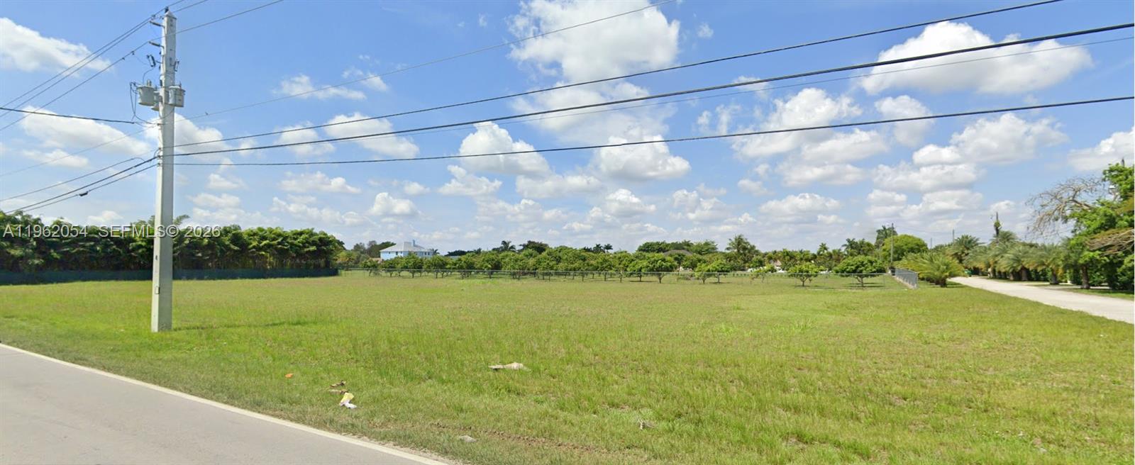 A large, flat, grassy vacant lot is bordered by trees and a paved road — 21220 SW 194 AVE, Miami FL 33187, MIAMI, FL