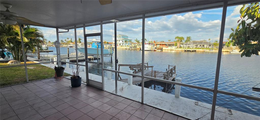 A screened-in patio overlooks a canal with a private dock and several boats — 5308 PILOTS PLACE, NEW PORT RICHEY, FL