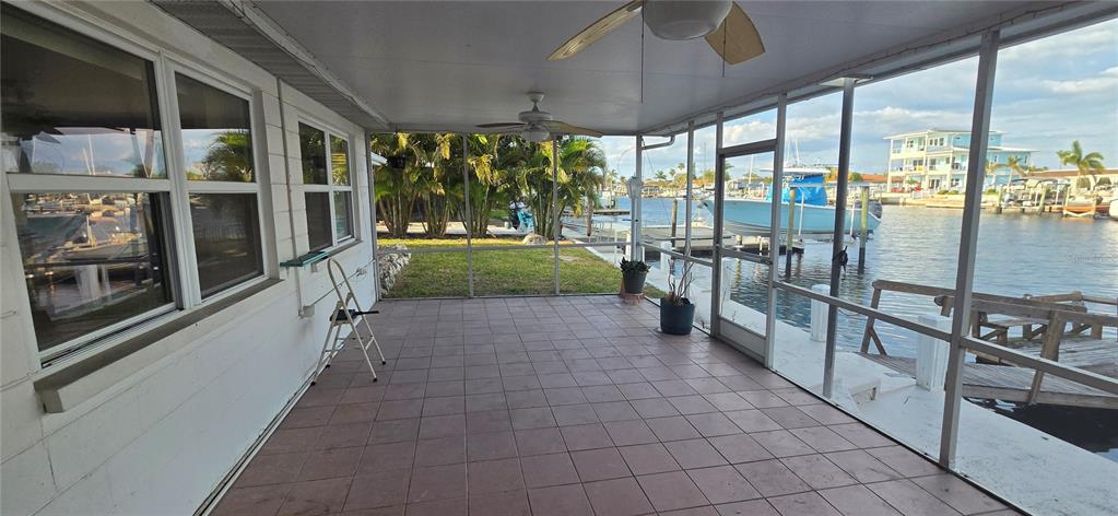 A screened-in porch with tiled flooring overlooks a canal with boats and a dock — 5308 PILOTS PLACE, NEW PORT RICHEY, FL