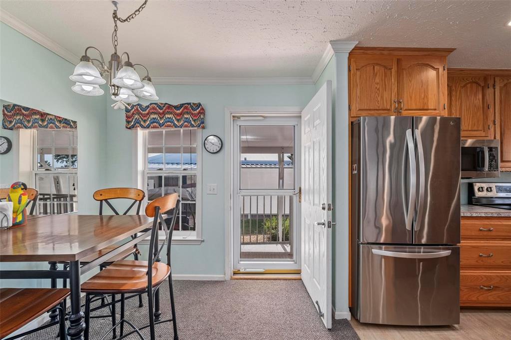 A dining area with a wooden table, chairs, stainless steel refrigerator, and a glass door — 1000 KINGS HIGHWAY UNIT 175, PORT CHARLOTTE, FL