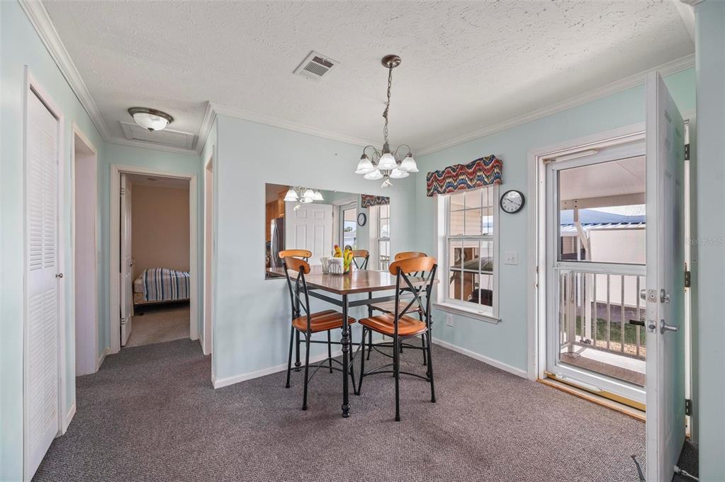 A dining area features a small table with four chairs, a mirror, and carpeted flooring — 1000 KINGS HIGHWAY UNIT 175, PORT CHARLOTTE, FL