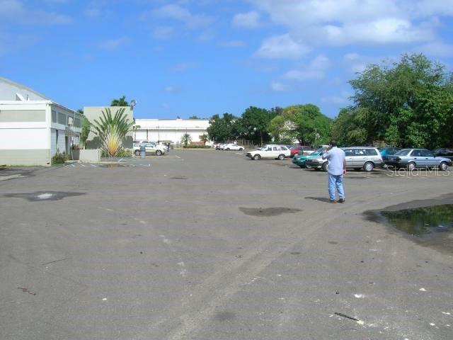 A person stands in a large, paved parking lot next to a commercial building — Lot No. 9-B ISABELA INDUSTRIAL PARK PR 112 KM 2.3, ISABELA, PR