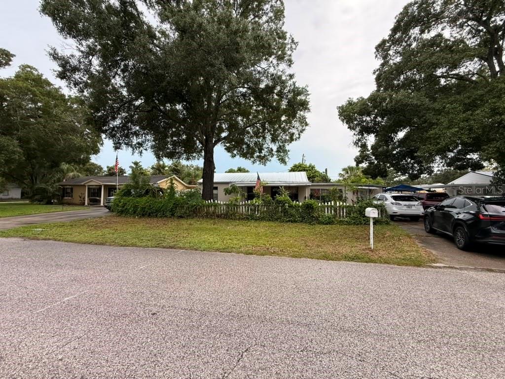 A single-story house with a white picket fence, large trees, and a driveway with cars — 4203 S TRASK STREET, TAMPA, FL