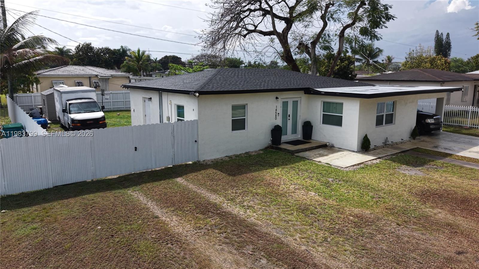 A single-story white house with a dark roof, a carport, and a fenced side yard — 14580 Harrison St, Miami FL 33176, MIAMI, FL