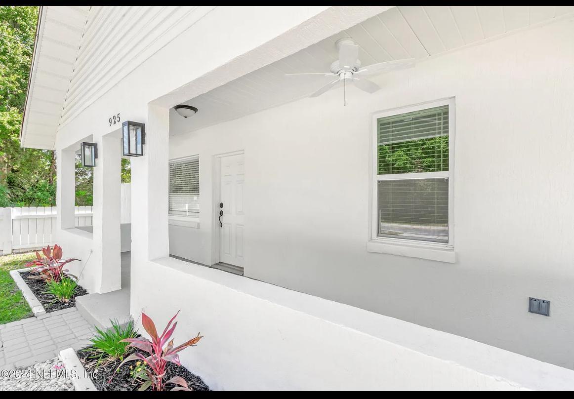 A white covered porch features a ceiling fan, a door, and a window — 925 S St. John Street, FL 32084, FL