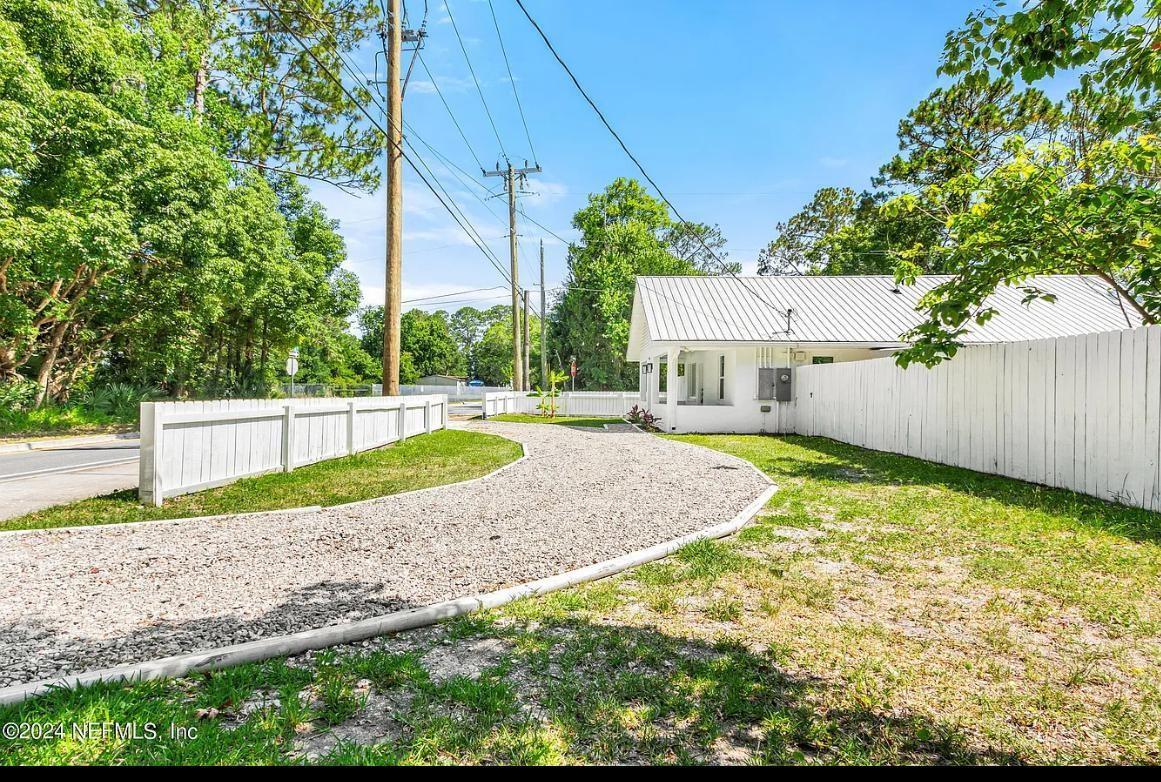A gravel driveway leads to a white house with a metal roof and fenced yard — 925 S St. John Street, FL 32084, FL