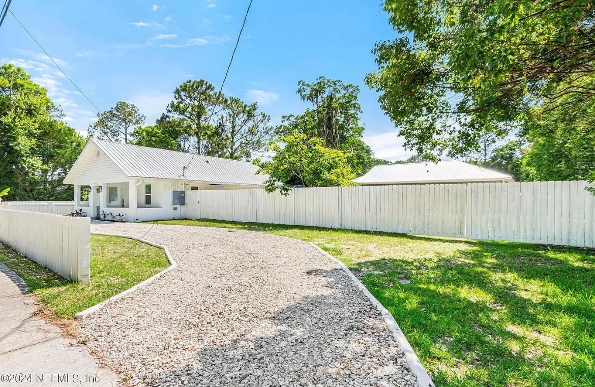 A white house with a metal roof sits behind a white wooden fence and driveway — 925 S St. John Street, FL 32084, FL