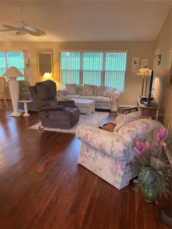 A living room features hardwood floors, a floral armchair, a recliner, and a sofa — 8744 SW 108TH LANE ROAD, OCALA, FL