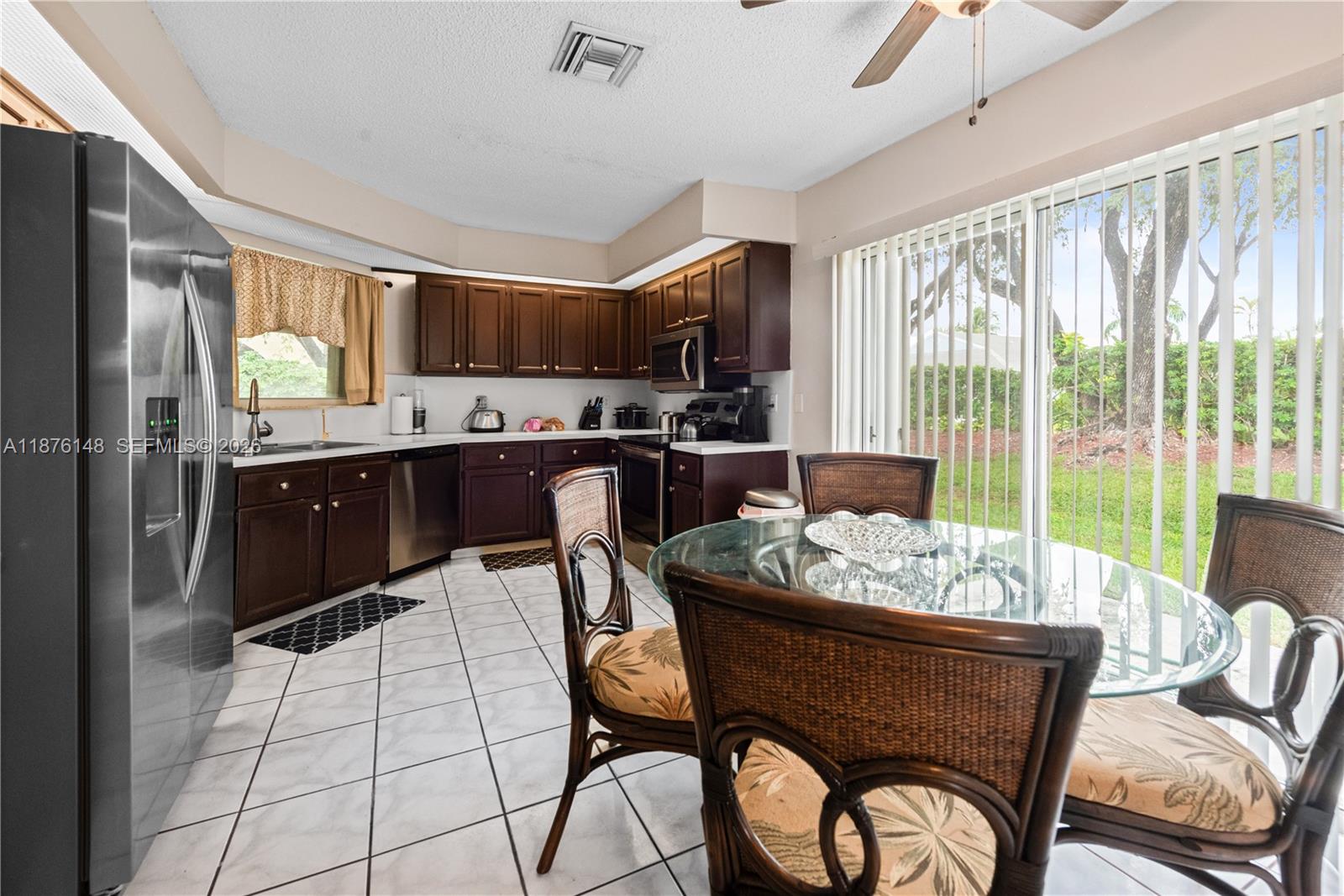 A kitchen features dark wood cabinets, stainless steel appliances, tile flooring, and a dining area — 2585 SE 7th Pl, Homestead FL 33033, HOMESTEAD, FL