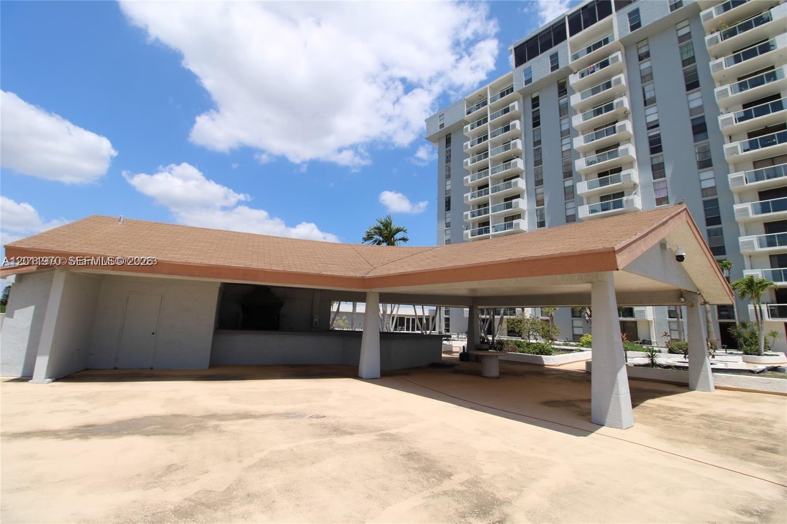 An outdoor covered pavilion with a bar area sits beside a tall residential apartment building — 13499 Biscayne Blvd # 404, North Miami FL 33181, NORTH MIAMI, FL